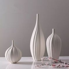 three white vases sitting next to each other on a table