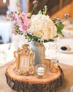 a vase filled with white and pink flowers on top of a wooden table next to a mirror