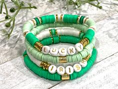 three bracelets with white and green beads on top of each other next to flowers