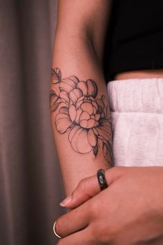 a woman's arm with a flower tattoo on the left side of her arm