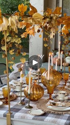 the table is set with candles, plates and glasses for fall dinner guests to enjoy