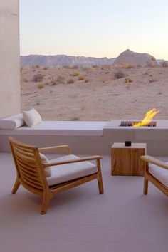 two wooden chairs sitting next to each other on top of a cement floor near a fire pit