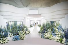 the bride and groom are walking down the aisle in their wedding dress, which is decorated with blue and white flowers