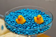 two rubber ducks in a bowl of blue candy