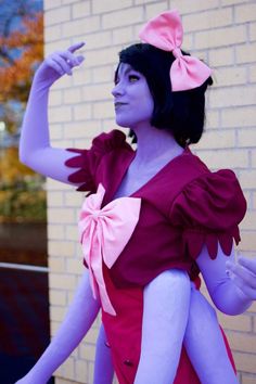 a woman dressed in purple and pink poses for the camera