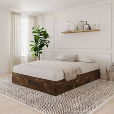 a bed sitting on top of a wooden floor next to a plant in a bedroom