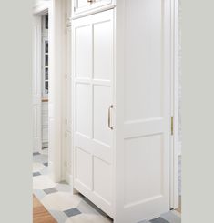 an open white door in the middle of a room with checkered flooring and walls