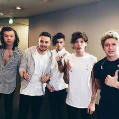 five young men posing for the camera in front of a mirror with their thumbs up