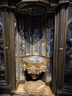 an ornate display case in the shape of a vase with a glass window behind it