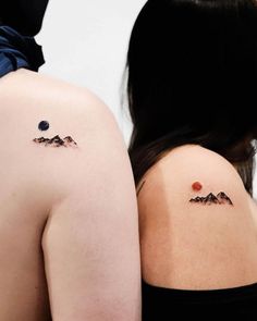 the back of two women's shoulder tattoos with mountains and stars on them,