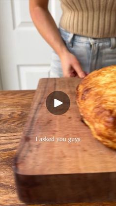 a person standing in front of a wooden cutting board with a pastry on top of it