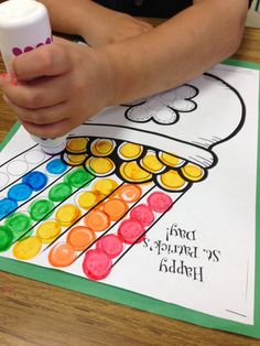 a child's hand is holding a white cup with colored crayons on it