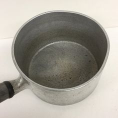 a metal pan with a handle on a white surface