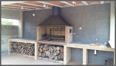 an outdoor kitchen with wood stacked on the counter and a brick oven in the middle