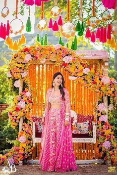 a woman standing in front of a decorated stage with flowers and hanging decorations on it