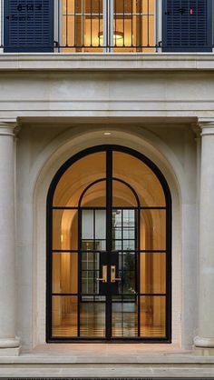 the front entrance to a large white building with blue shutters on it's windows