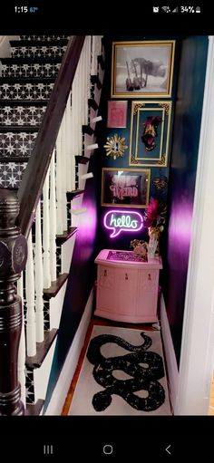 the stairs in this house are decorated with black and white wallpaper, pink trunk under the staircase