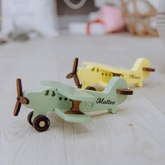 two small wooden toy airplanes sitting on top of a white table next to each other