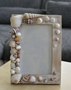 a frame with seashells on it sitting on a table next to a couch