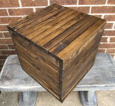 a wooden box sitting on top of a cement bench next to a brick wall and sidewalk