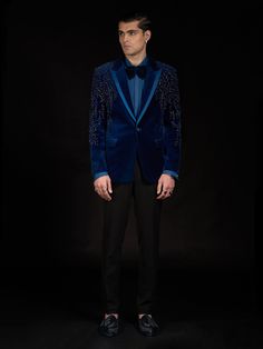 Sapphire tuxedo jacket with on-shoulder adornment and satin lapel, paired with matching trousers. Embroidery Details: Embroidered With Metallic Sequins, Cut Beads And Crystals. Embellished Notch Lapel Suits For Semi-formal Occasions, Tailored Embellished Sets For Party, Luxury Party Suits With Lapel Collar, Luxury Lapel Collar Suits For Party, Luxury Suits With Notch Lapel For Night Out, Elegant Sequined Suits For Evening, Tailored Embellished Evening Sets, Tailored Embellished Sets For Evening, Luxury Embellished Suit With Notch Lapel