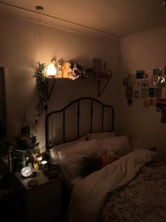 an unmade bed in a dimly lit room with pictures on the wall above it