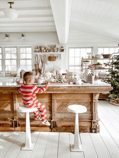 a little boy sitting on top of a stool in a kitchen next to a counter