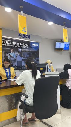 several people sitting at a counter in front of televisions and signs on the wall