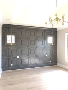 an empty room with wood floors and gray wallpaper on the walls, light fixtures in the corner