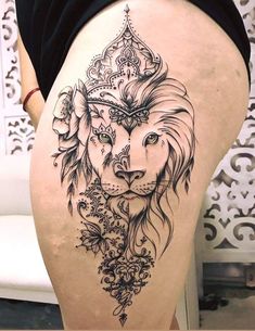 the back of a woman's thigh with a lion and flowers tattoo on it