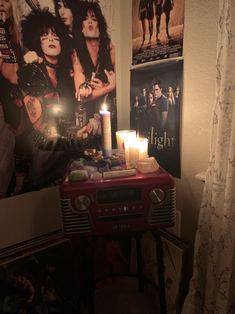 a red radio sitting on top of a table next to a wall covered in posters