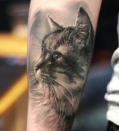 a black and grey cat tattoo on the left arm, with an eye looking straight ahead