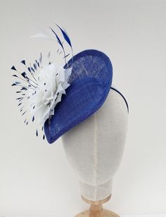 Bright blue fascinator/hatinator. I have made this striking fascinator in bright blue sinamay/straw. I have decorated it with a large hand made feather flower and clipped bright blue and white feathers. It is secured with a fine metal covered headband which can easily be hidden by your hair if desired. One size fits all Summer Sinamay Headpiece For Races, Blue Spring Headpieces For Events, Blue Headpieces For Spring Events, Blue Curved Brim Summer Costume Hat, Blue Fascinator With Short Brim For Summer, Blue Short Brim Fascinator For Summer, Blue Fascinator With Curved Brim For Spring, Blue Summer Fascinator Hat, Blue Curved Brim Fascinator For Spring