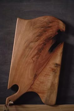 a wooden cutting board sitting on top of a black table next to a pair of scissors