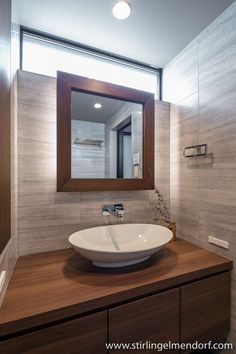 a bathroom sink sitting under a mirror next to a wooden counter topped with a white bowl