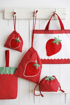 three red strawberry bags hanging on a white wall