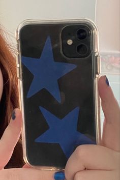 a woman holding up her phone case with blue stars on the front and back cover