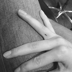 a person's hand with a tiny cross tattoo on their left thumb and fingers