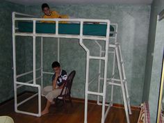 two people sitting on bunk beds in a room with green walls and wood flooring