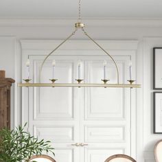 a chandelier hanging over a dining room table with two chairs and a potted plant