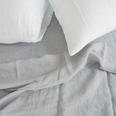 two white pillows on top of a bed with sheets pulled back to reveal the comforter