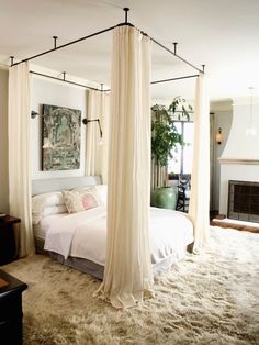 a bedroom with four post bed and white drapes