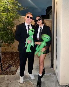 a man and woman dressed up in costume posing for a photo with a green frog