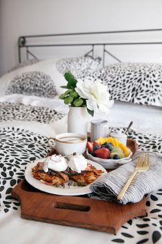 a breakfast tray with fruit, yogurt, and coffee on top of a bed