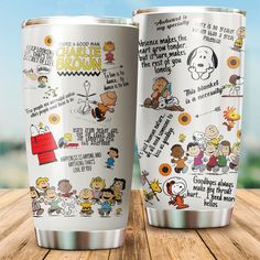 two stainless steel tumblers with peanuts sayings on them sitting on a wooden table