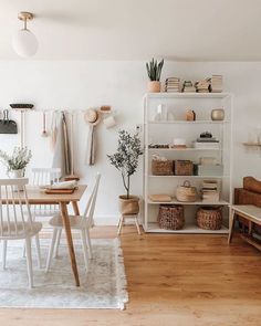 a dining room with white walls and wooden flooring next to a bookshelf