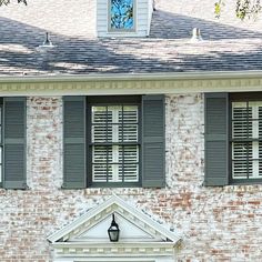 an old brick building with shutters and a clock on the front door is shown