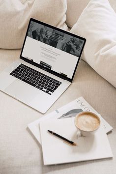 an open laptop computer sitting on top of a couch next to a cup of coffee