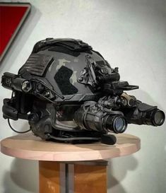 a helmet is sitting on top of a wooden stand with two binoculars in it's mouth