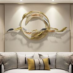 a living room with a white couch and gold accents on the wall above it is a circular metal art piece